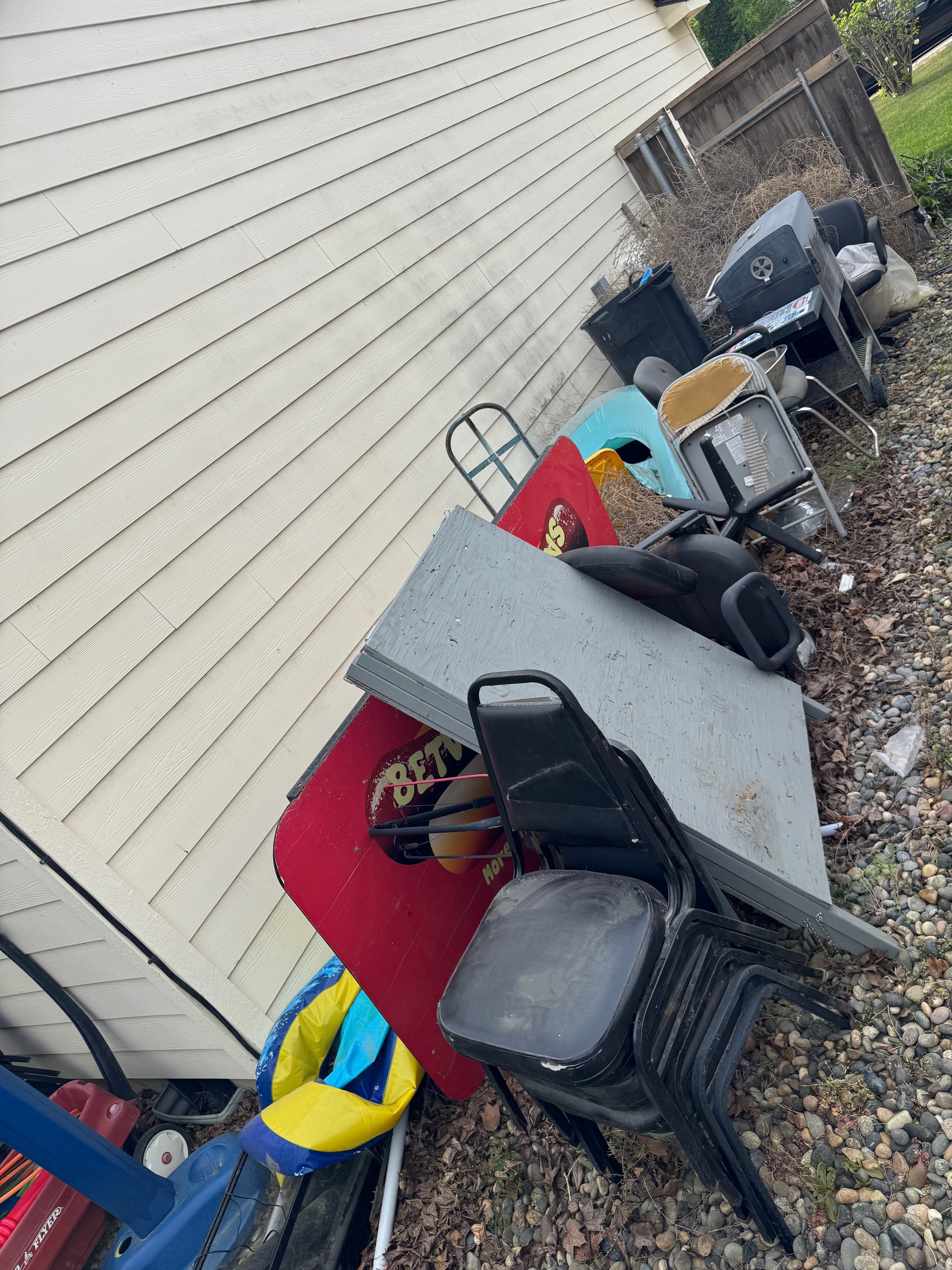 Bulky outdoor items, stacked chairs, panels, and debris before junk removal