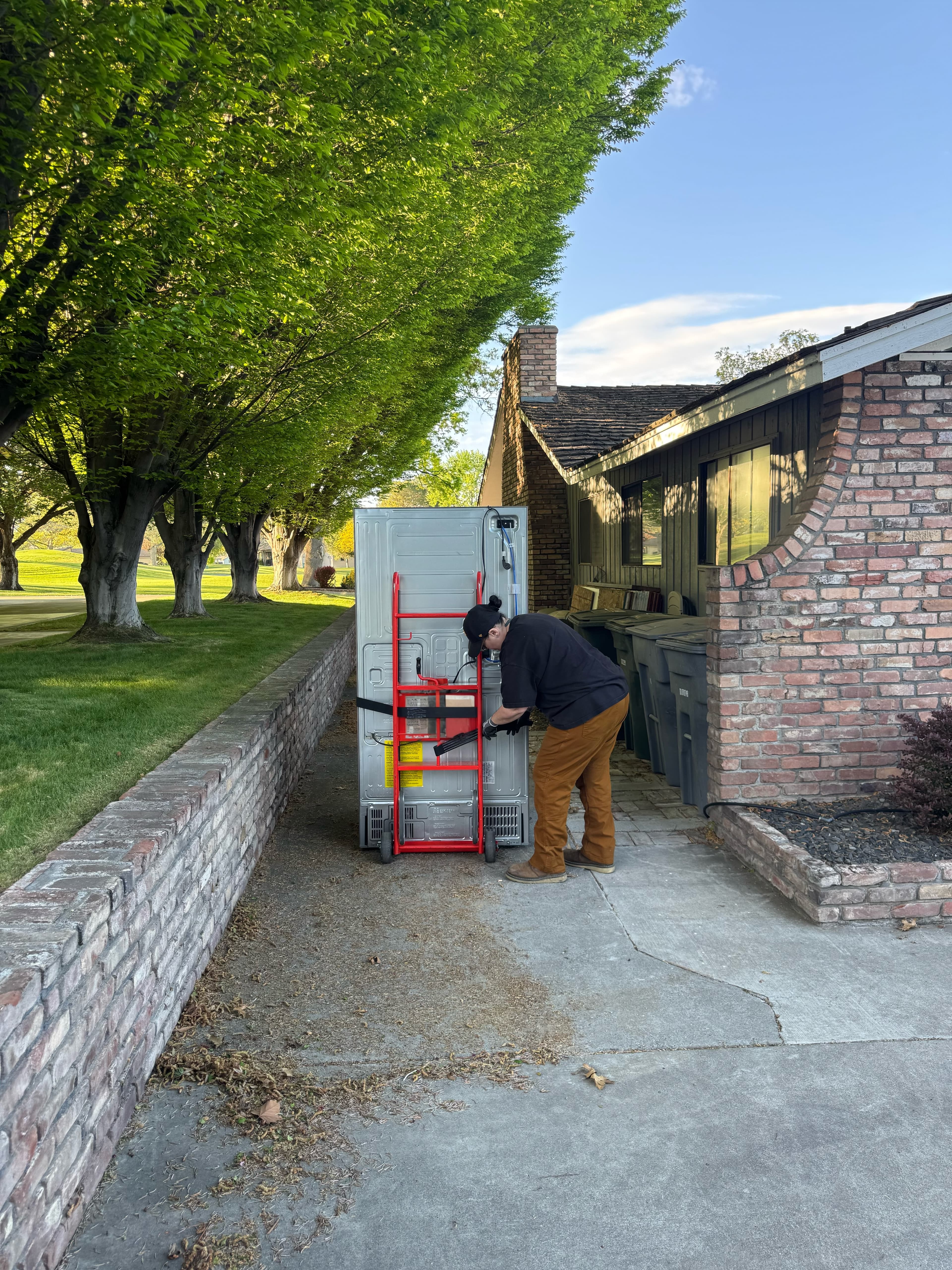 Refrigerator removal with crew member using dolly and tools to load and haul away