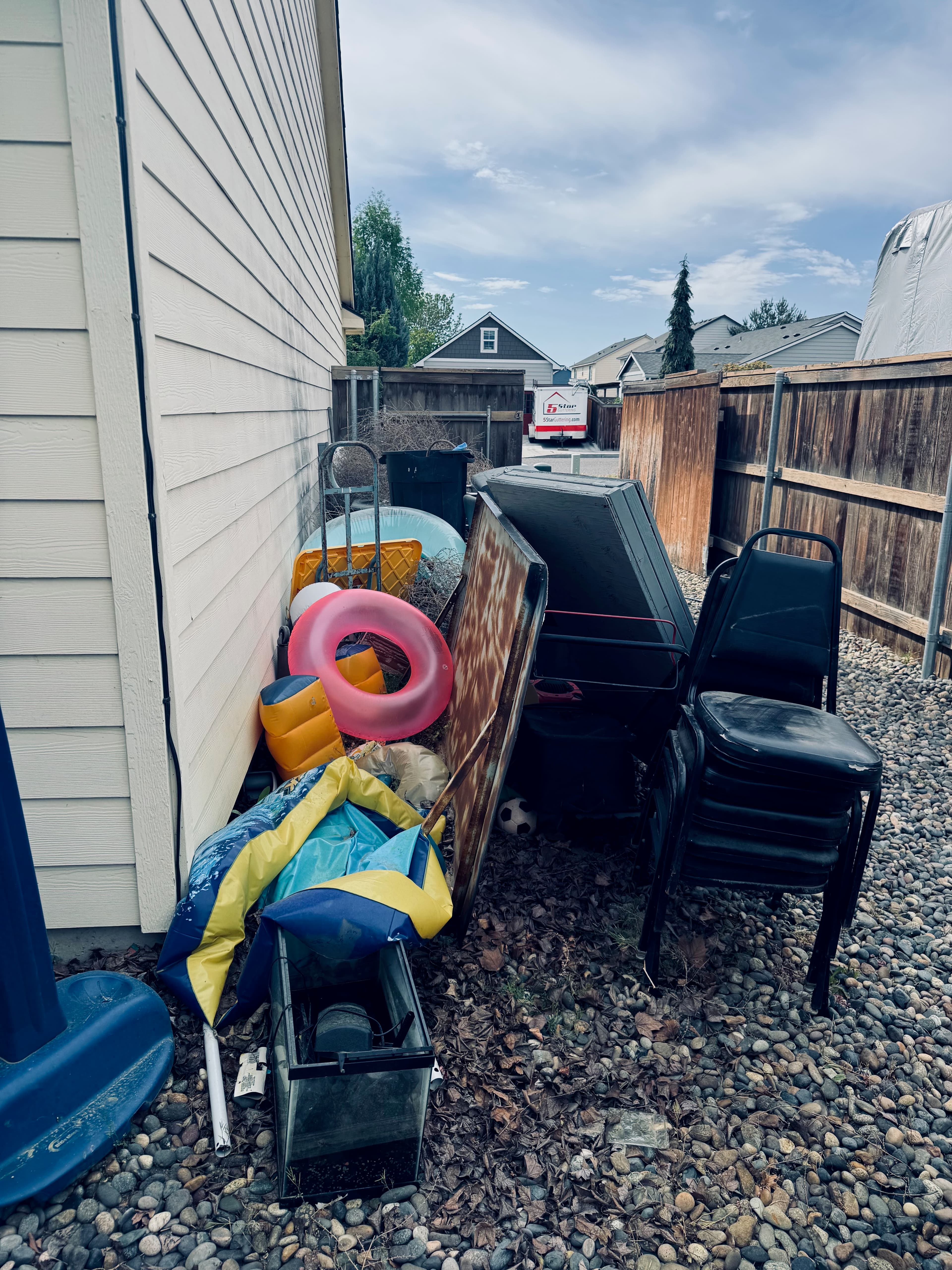 Cluttered outdoor space before junk removal with garage and fence visible